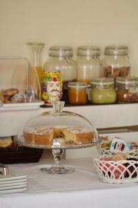 a cake in a glass dish on a counter with jars of food at La Guitgia Rooms in Lampedusa