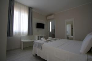 a white bedroom with a large bed and a bathroom at La Guitgia Rooms in Lampedusa