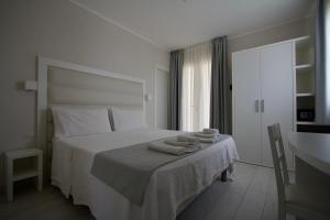a white bedroom with a bed with towels on it at La Guitgia Rooms in Lampedusa