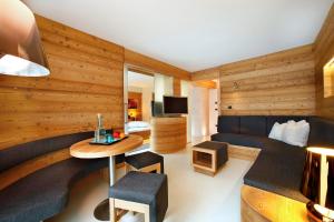 ein Zimmer mit Holzvertäfelung und ein Wohnzimmer in der Unterkunft Hotel Valpudra in Wolkenstein in Gröden + 50 Fotos