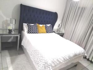 a bedroom with a bed with a blue headboard and pillows at The Blyde Riverwalk Estate, R104 Bronkhorstspruit Road in Pretoria