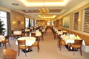 un restaurant avec des tables et des chaises blanches et un lustre dans l'établissement Gesundheitsresort Bad St. Leonhard, à Bad Sankt Leonhard im Lavanttal
