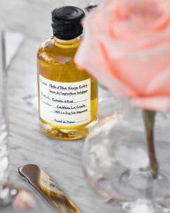 a bottle of oil next to a flower and a wine glass at Cara Hotel in Los Angeles