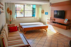 a living room with a bed and a couch and a television at Apartamento no Condomínio Varandas do Sol in Porto Seguro