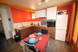 a kitchen with a table and a kitchen with red walls at Le Balcon des Charmottes in Névache