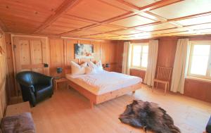 ein Schlafzimmer mit einem Bett und einem schwarzen Stuhl in der Unterkunft WÄLDERHAUS Apartments in Schwarzenberg im Bregenzerwald