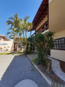 a house with palm trees in front of it at Pousada Mar e Marés in Rio das Ostras