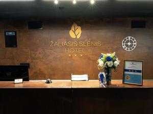 a hotel lobby with a reception desk with flowers on it at Zaliasis slenis - Self check-in hotel in Klaipėda