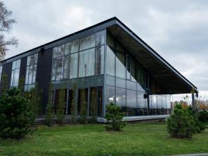 a large building with glass windows in a field at Zaliasis slenis - Self check-in hotel in Klaipėda