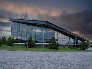 克莱佩达Zaliasis slenis - Self check-in hotel - Free parking的一座大型玻璃建筑,前面有一个钟