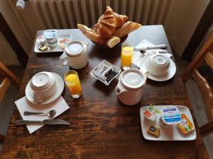 - une table avec de la nourriture pour le petit-déjeuner, du jus d'orange et du pain dans l'établissement Hôtel Restaurant Le Moulin de la Renne Adults Only proche Zoo de Beauval, à Thésée