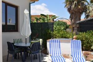 Un patio con una mesa y sillas y una sombrilla. en In Riva al Mare da Franca, en Trabia