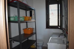 Un estante negro en un baño con inodoro y ventana. en In Riva al Mare da Franca, en Trabia