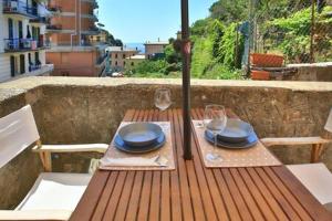 uma mesa de madeira com pratos e óculos e um guarda-chuva em Jolly Roger Riomaggiore em Riomaggiore