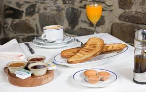 una mesa con un plato de tostadas y un vaso de zumo de naranja en Hotel Rural Valle de Ancares, en Pereda de Ancares