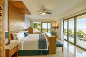 a bedroom with a bed and a view of the ocean at Sensira Resort & Spa Riviera Maya All Inclusive in Puerto Morelos