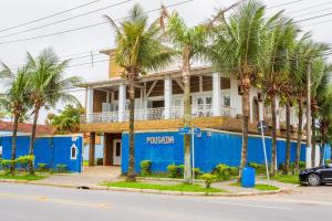 un bâtiment bleu avec des palmiers devant lui dans l'établissement Pousada Hotel Canto dos Mares, à Guarujá
