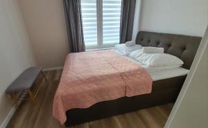 a small bed with a pink blanket and a window at Apartamenty Waterline Ustronie Morskie in Ustronie Morskie
