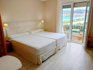 um quarto de hotel com duas camas e uma varanda em Rodeiramar 2A em Cangas