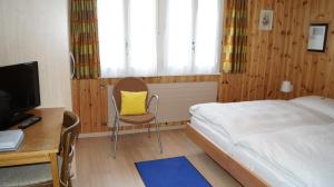 ツェルマットにあるHotel Alpinaのベッドルーム1室(ベッド1台、デスク、黄色い枕付)