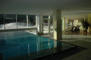 a swimming pool in a house with a view of the snow at Romantik Resort & SPA Der Laterndl Hof in Haldensee