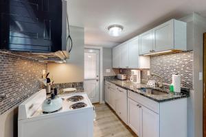 a kitchen with white cabinets and a sink at Wild Wood Way Cottage in Bar Harbor