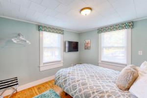 a bedroom with a bed and two windows at Wild Wood Way Cottage in Bar Harbor