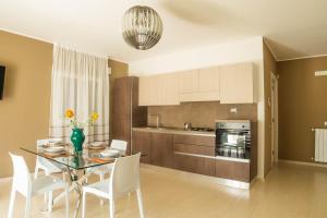 a kitchen with a glass table and white chairs at Independence House Holiday in Catania