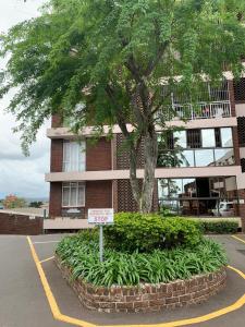 un panneau devant un bâtiment avec un arbre dans l'établissement Musgrave Seafern, à Durban