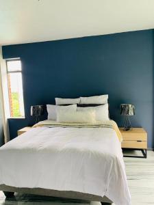 a bedroom with a blue wall and a white bed at Musgrave Seafern in Durban