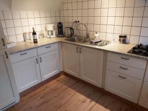 a kitchen with white cabinets and a sink at De Hammerhoeve in Dalfsen