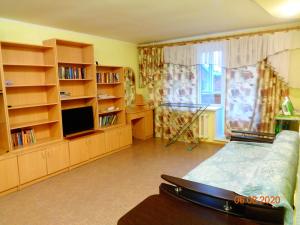 トムスクにあるАпартаменты 2-к Иркутский тракт 12のベッド、テレビ、棚が備わる客室です。