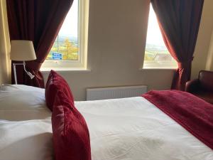 a bed with red pillows in a bedroom with two windows at The Wyche Inn in Great Malvern