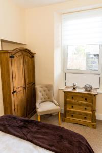 a bedroom with a dresser and a chair and a window at Stylish 2 bedroom, city centre apartment in Aberdeen