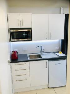a white kitchen with a sink and a microwave at Studio on Parkers in Nelson