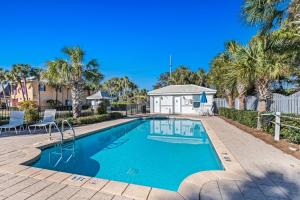 a swimming pool with palm trees and a house at Emerald Shores in Destin
