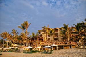 un complejo en la playa con palmeras y sombrillas en Mancora Beach Hotel - Adults Only, en Máncora