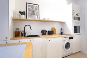 una cucina con armadi bianchi e una lavatrice/asciugatrice di Beautiful 45 m2 apartment in Paris a Parigi
