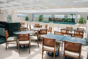 a restaurant with tables and chairs and a pool at Apart Hotel Diamond Flat 2 Quartos in Nova Iguaçu