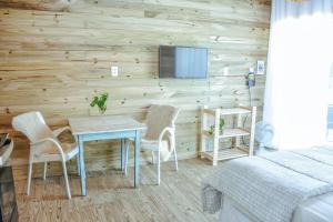 1 dormitorio con mesa, sillas y TV en la pared en Loft Casa no Farol, en Laguna