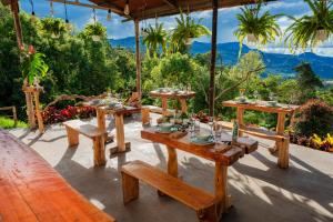 a table and benches on a patio with mountains in the background at Guaia Terra Glamping in Pacho