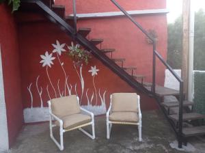 2 sillas sentadas junto a una escalera con un mural en Hosteling Las Margaritas, en Minas