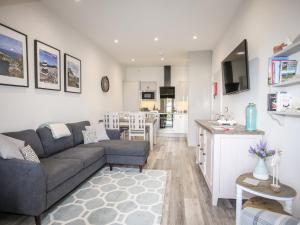 a living room with a couch and a kitchen at Puffin Pad in Benllech