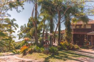 ein Haus inmitten eines Hofes mit Bäumen in der Unterkunft Pousada Caminho do Rei in Praia do Rosa