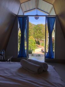布羅莫的住宿－布羅莫營地之家，一张位于带蓝色窗帘窗户的房间里的床