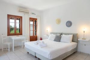 a bedroom with a large white bed and a desk at Blue Fish in Platis Yialos Sifnos