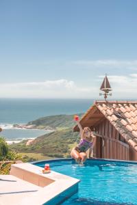 a little girl playing with a ball in a swimming pool at Pousada Caminho do Rei in Praia do Rosa