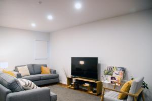 a living room with two couches and a flat screen tv at Whakatane B&B in Whakatane