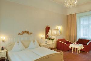 a bedroom with a large white bed and a chair at Pertschy Palais Hotel in Vienna