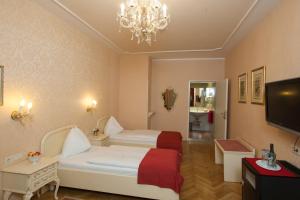 ウィーンにあるペルチー パレ ホテルのベッド2台とシャンデリアが備わるホテルルームです。